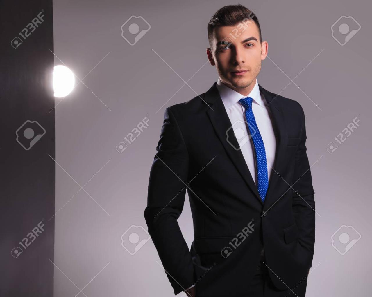 Man In Black Suit With Blue Tie Standing With Hands In His Pockets Being  Fashion Stock Photo, Picture And Royalty Free Image. Image 117534922.